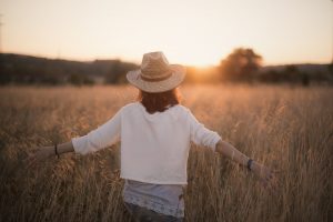 The Power of choice. A woman walking in the field at sunset.